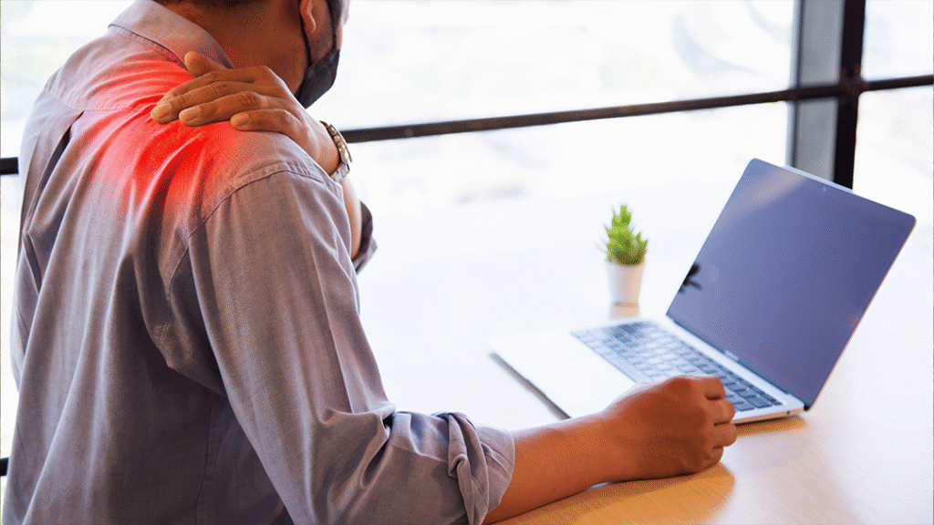 Man with shoulder pain working on laptop