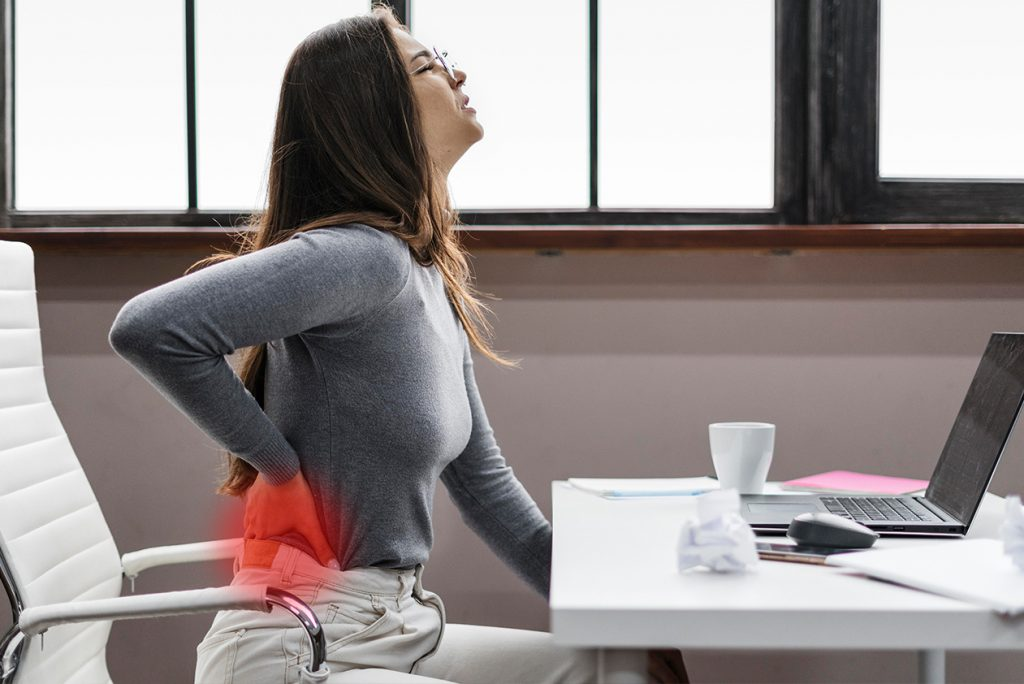 Woman experiencing back pain from prolonged sitting at work