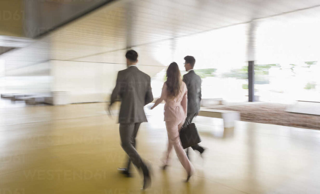 3 businesspeople walking in the office lobby
