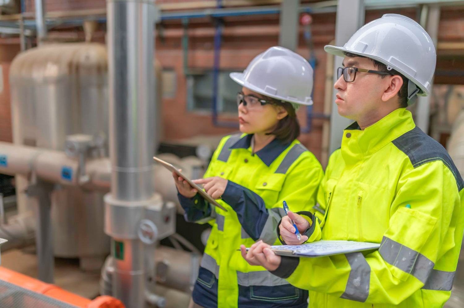 An expert using an ergonomics assessment checklist for manufacturing on a tablet in a factory setting.