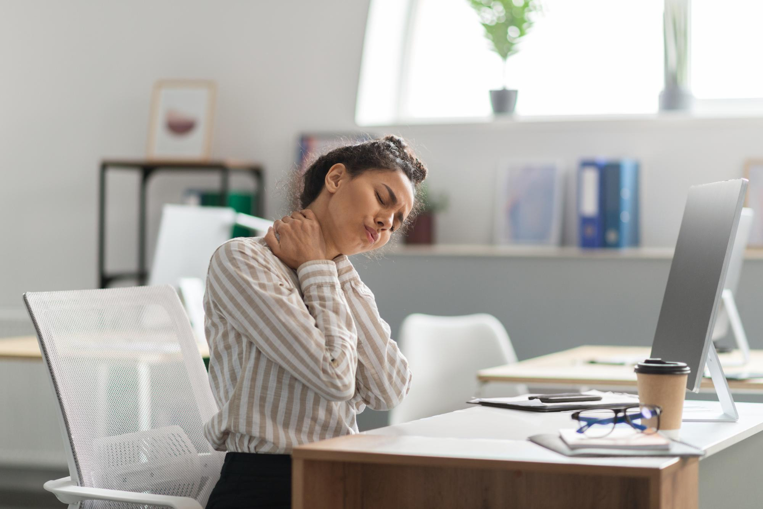 An office worker experiencing neck strain, a sign that her ergonomics assessment for office workers may have missed key issues.