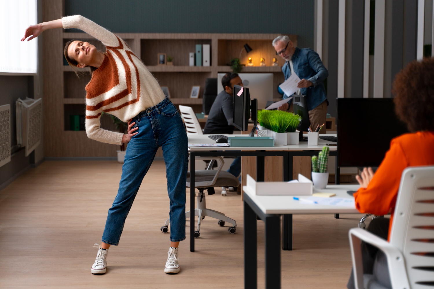 Employees taking a stretch break in an office, promoting movement.