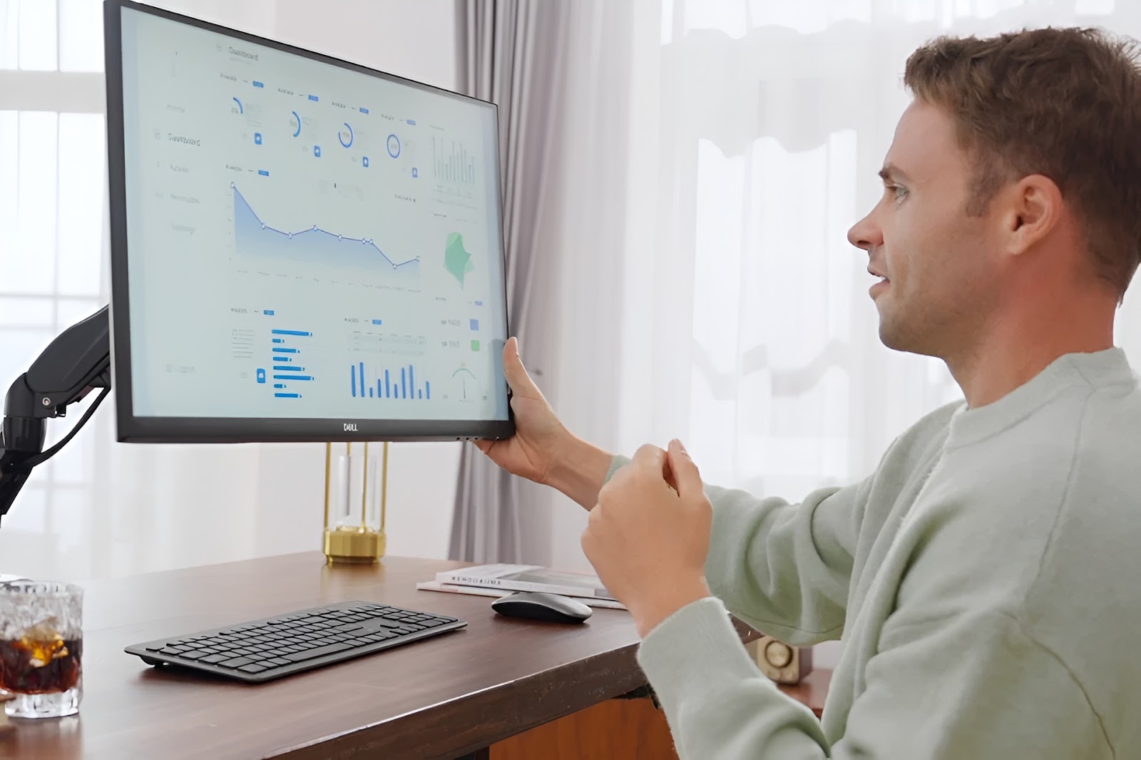 Person adjusting monitor height with a monitor arm.