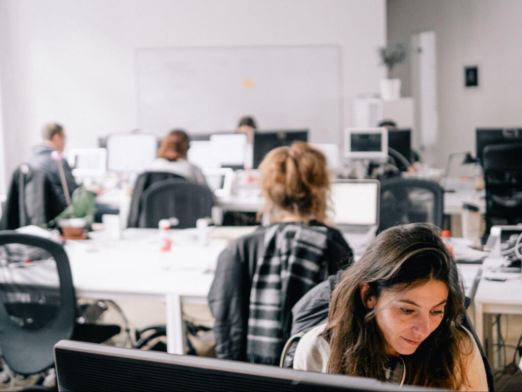 Diverse group of employees happily collaborating in a modern office, highlighting the benefits of well-designed ergonomics.