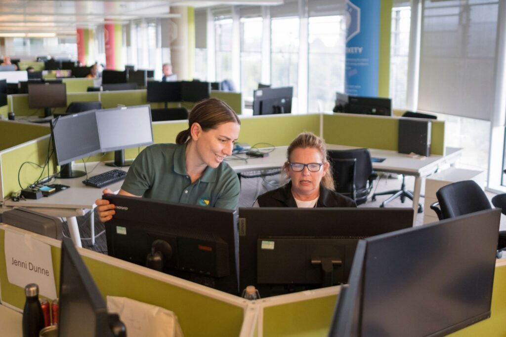 Ergonomist consultant giving guidance to an employee at a desk. 