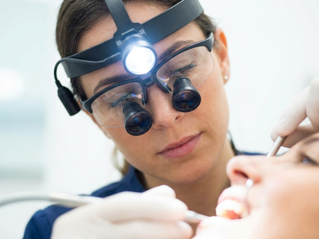Close-up of a dental hygienist wearing loupes and a headlight. 
