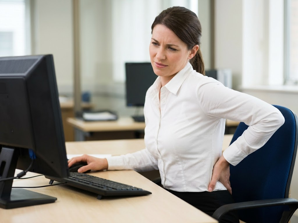Employee in pain at a non-ergonomic desk. 