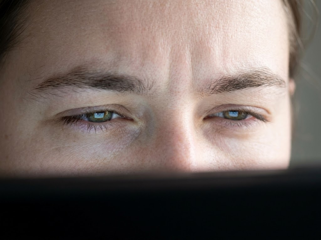 Person's eyes squinting due to screen glare. 
