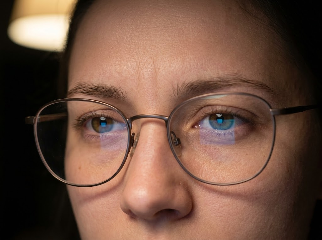 A close-up of squinting eyes reflecting cool screen light.Â
