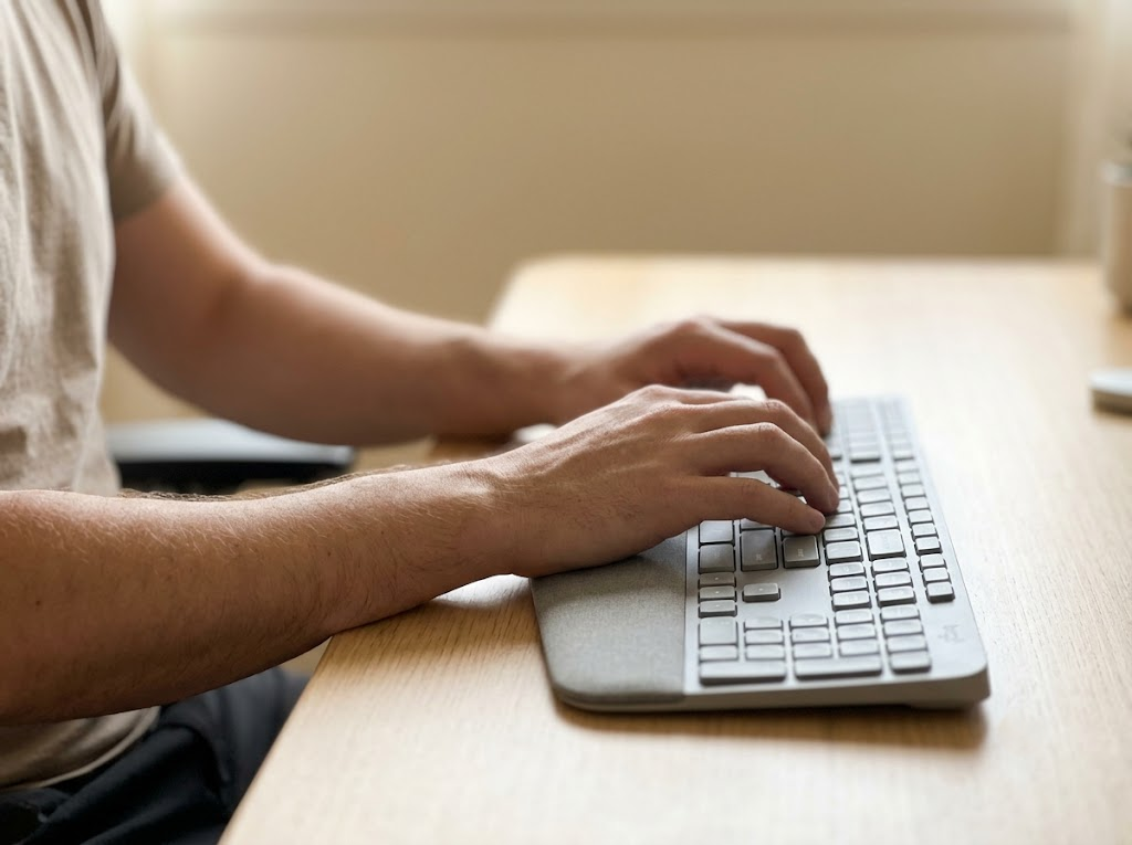 Person typing at desk in seated repetitive posture 